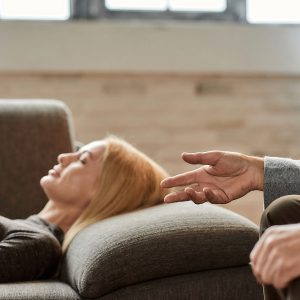 Psychoanalyst Talking To Calm Young Caucasian Woman Lying On Sof
